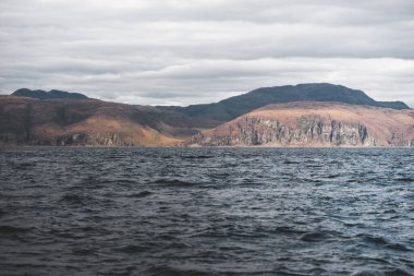 Yat manzaralı Jura adasının batı kıyısındaki kayalık kıyılara (uçurumlara) yelken açmak. Fırtınadan sonra dramatik bulutlar. Inner Hebrides, İskoçya, İngiltere. Atmosferik manzara