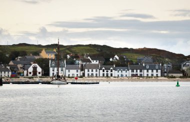 Gün doğumunda küçük bir kasaba olan Port Ellen 'ın kayalık sahili. Sabah güneşi. Köy evleri, balıkçı tekneleri ve yatlar yakın plan. Islay Adası, Inner Hebrides, İskoçya, İngiltere