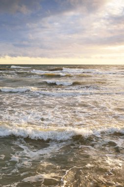 Gün batımında fırtınadan sonra Baltık Denizi. Letonya 'da sızıntı var. Renkli parlayan bulutlar. Dalgalar ve su sıçramaları. Destansı deniz manzarası. Kasırga, fırtına, dönek hava, meteoroloji, ekoloji
