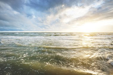 Gün batımında fırtınadan sonra Baltık Denizi. Letonya 'da sızıntı var. Renkli parlayan bulutlar. Dalgalar ve su sıçramaları. Destansı deniz manzarası. Kasırga, fırtına, dönek hava, meteoroloji, ekoloji
