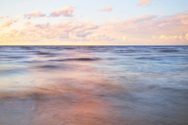 Gök gürültülü bir fırtınadan sonra denizin üstünde destansı pembe gün batımı bulutları. Dramatik bir gökyüzü. Dalgalar ve su dokuya sıçrar. Idyllic deniz manzarası. Kavramsal görüntü, uzun pozlama. Resim gibi bir manzara.