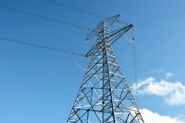 Elektrik hattı açık mavi gökyüzüne karşı, yakın plan. Şehir manzarası kavramı. Enerji, enerji üretimi, özel ekipman, endüstri, çevresel hasar, ekoloji, altyapı, ormanların tahrip