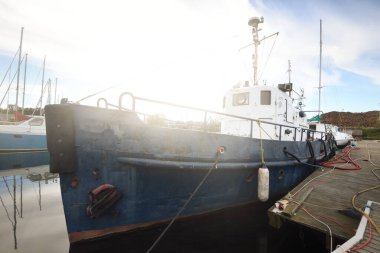 Eski mavi römorkör gemisi. Açık bir yaz gününde yat ve tekneler yat limanındaki bir rıhtıma demirlemişti. Riga, Letonya. Tatiller, spor, amatör eğlence yelkenciliği, balıkçılık, sanayi, geleneksel zanaat