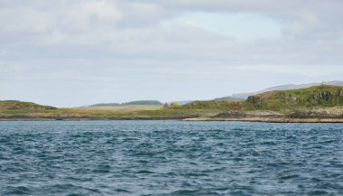 Jura adasının kıyılarının panoramik manzarası, dağları ve vadileri sudan. Bulutlu mavi gökyüzü. Paps of Jura, Inner Hebrides, İskoçya, İngiltere