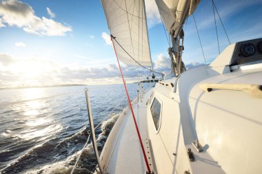Günbatımında yağmurdan sonra beyaz yat denize açılacak. Güverteden pruvaya kadar yakın çekim. Renkli altın ve pembe bulutlarla parlayan parlak bir gökyüzü. Idyllic deniz manzarası. Deniz, seyahat, seyahat yerleri