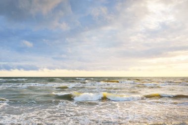 Gün batımında fırtınadan sonra Baltık Denizi. Letonya 'da sızıntı var. Renkli parlayan bulutlar. Dalgalar ve su sıçramaları. Destansı deniz manzarası. Kasırga, fırtına, dönek hava, meteoroloji, ekoloji