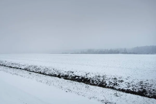 暴风雪过后 覆盖着白雪的乡间小路穿过田野 变压器杆 从车上俯瞰全景 黑暗的暴风雨的天空 冬季轮胎 偏远村庄 — 图库照片