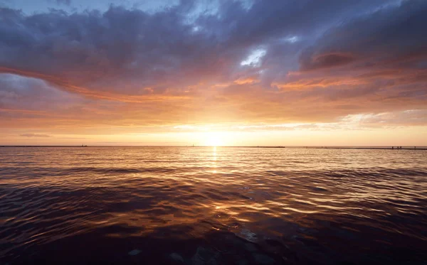 日没のバルト海 水の中に反映輝く雲と劇的な空 背景に灯台 太陽を沈める 壮大な海の景色 アブストラクト自然パターン テクスチャ コンセプトイメージ — ストック写真