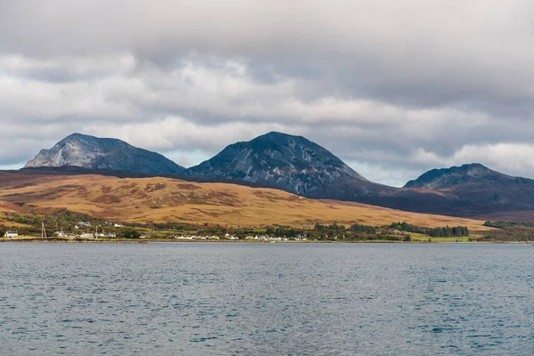 Panoramic view of the rocky shore near the mountain peaks of Paps of Jura under dramatic sunset sky. A view from the yacht. Jura island, Inner Hebrides, Scotland, UK. Travel destinations, landmarks