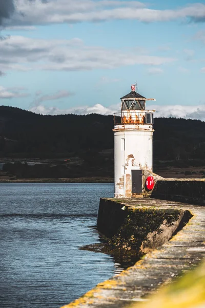 Eski deniz fenerine doğru boş bir gezinti, yakın plan. Arka planda kayalık kıyılar var. Dramatik bulut manzarası. Ardrishaig, Crinan Kanalı, İskoçya, İngiltere. Seyahat yerleri, gezi teması