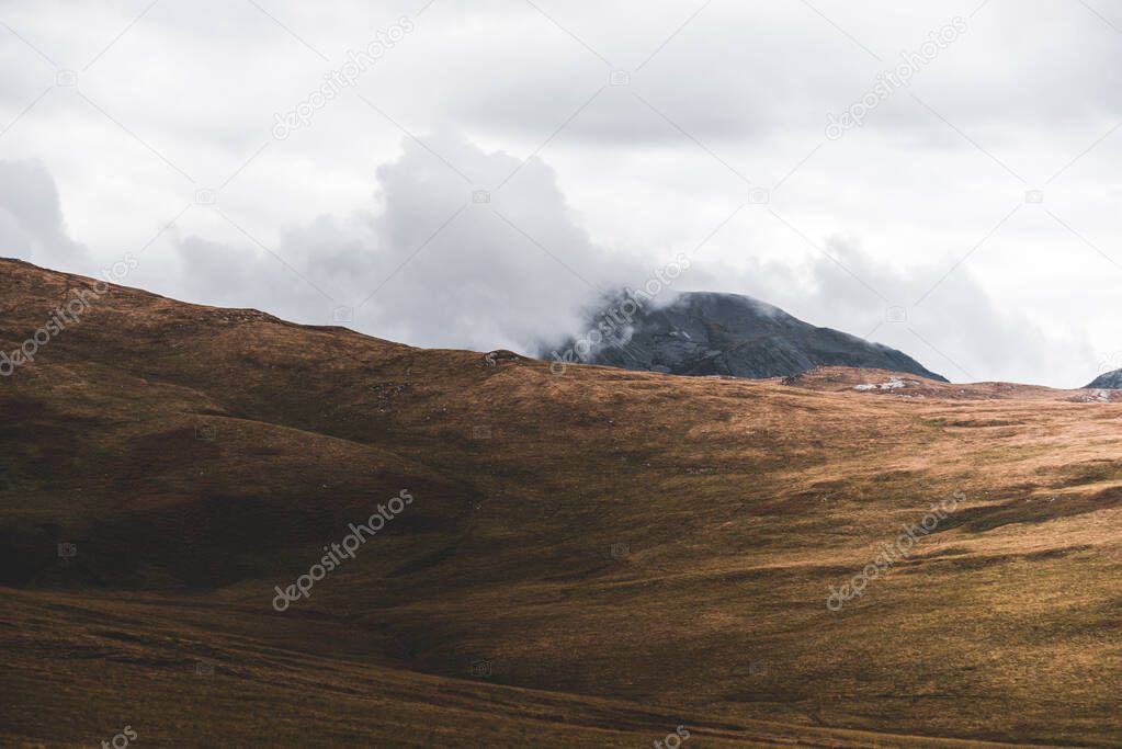 Panoramic view of the valley near the highest mountain peak of Paps of Jura (Beinn an ir) under the cloudy blue sky. Dramatic clouds. Jura island, Inner Hebrides, Scotland, UK. Atmospheric landscape.