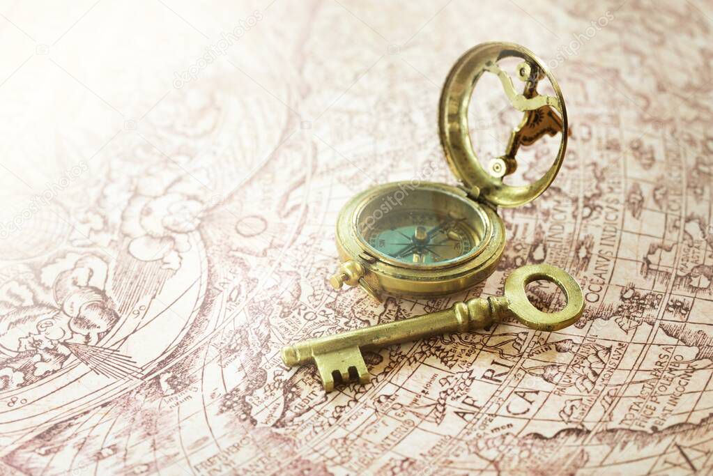 Retro styled golden antique compass (sundial) and old white nautical chart close-up. Vintage still life. Sailing accessories. Travel, navigation concepts, collecting, souvenir, gift, graphic resource