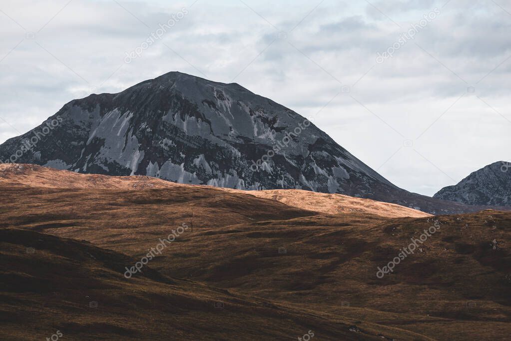 Panoramic view of the valley near the highest mountain peak of Paps of Jura (Beinn an ir) under the dark storm sky. Dramatic clouds. Jura island, Inner Hebrides, Scotland, UK. Atmospheric landscape.