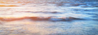 Deniz dalgaları ve sıçrama dokusu. Renkli gökyüzü suya yansıyor. Idyllic deniz manzarası. Sanat kavramı, uzun pozlama. Resimli bir manzara var. Arkaplan, doğal düzen, grafik kaynaklar, panoramik görünüm