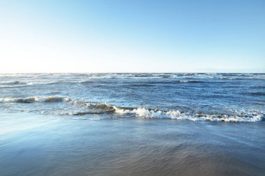 Gün batımında Baltık kıyılarından bir manzara. Açık mavi akşam gökyüzü, dalgalar ve su sıçramaları. Idyllic deniz manzarası. Letonya