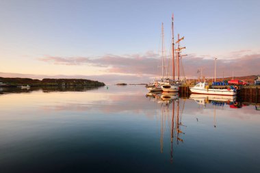 Sailboats moored to a pier, close-up. A view of the shore of a small town Port Ellen at sunrise. Isle of Islay, Inner Hebrides, Scotland, UK clipart