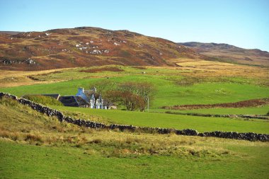 Islay adasının yeşil kıyılarının, vadilerinin ve tepelerinin panoramik manzarası. Köy evine yakın çekim. Inner Hebrides, Argyll ve Bute, İskoçya, İngiltere