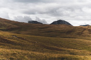 Bulutlu mavi gökyüzünün altındaki Paps of Jura 'nın (Beinn an ir) en yüksek dağı yakınındaki vadinin panoramik manzarası. Dramatik bulutlar. Jura Adası, Inner Hebrides, İskoçya, İngiltere. Atmosferik manzara.