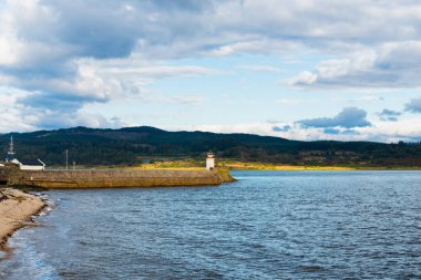 Eski deniz fenerine doğru boş bir gezinti, yakın plan. Arka planda kayalık kıyılar var. Dramatik bulut manzarası. Ardrishaig, Crinan Kanalı, İskoçya, İngiltere. Seyahat yerleri, gezi teması