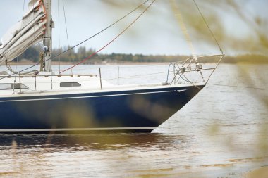 Kumsalın yakınındaki sığ sulara demir atmış ve yemyeşil ormanlara yakın. Lule Nehri, İsveç. Seyahat yerleri, spor, amatör yelkencilik.