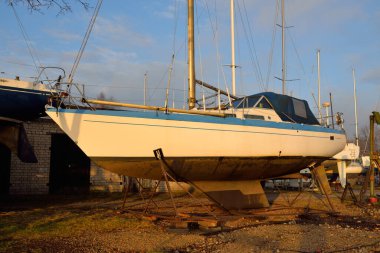 Kışlık şalopa donanımlı yat karada duruyor, yakın plan. Yeni yelken sezonunu bekliyorum. Gün batımında yat kulübü (marina). Yumuşak akşam ışığı. Denizcilik gemisi, servis, ulaşım