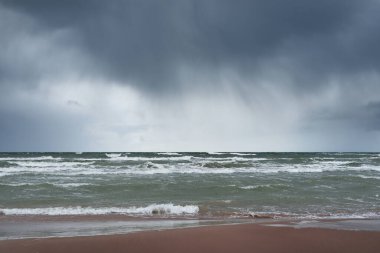 Fırtına sonrası dramatik bulutların altında Baltık Denizi 'nin kumlu sahili. Letonya 'da sızıntı var. Destansı deniz manzarası. Kasırga, fırtına, sert hava, meteoroloji, iklim değişikliği, doğal fenomen