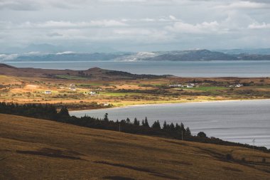 Jura adasının kıyıları, dağları ve vadilerinin panoramik hava manzarası. Bulutlu mavi gökyüzü. Fırtınalı hava. Paps of Jura, Inner Hebrides, İskoçya, İngiltere. Seyahat yerleri, turizm, ulusal simgeler
