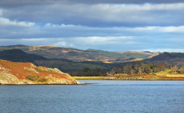 Denizden Crinan 'ın kayalık kıyıları ve ormanlarının manzarası. Argyll ve Bute, İskoçya, İngiltere