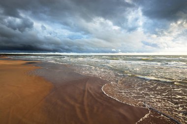 Sandy Baltık deniz kıyısı. Gün batımında fırtınadan sonra. Letonya 'da sızıntı var. Destansı deniz manzarası. Kasırga, fırtına, kararsız hava, meteoroloji, iklim değişikliği, doğal olay