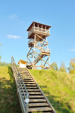 Letonya 'nın göl kıyısındaki modern ahşap kuş gözlem kulesine giden merdivenin alçak açılı görüntüsü. Açık mavi gökyüzü. Mimarlık, nesne, seyahat noktaları, eko turizm, çevre koruma