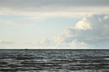 Gün batımında fırtınadan sonra Baltık Denizi 'nin üzerinde parlayan beyaz kümülüs bulutlarıyla açık bir gökyüzü. Dramatik bulut manzarası. Sıcak altın ışık. Resimli bir manzara var. Kararsız hava, iklim değişikliği