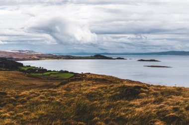 Jura adasının kıyıları, dağları ve vadilerinin panoramik hava manzarası. Bulutlu mavi gökyüzü. Fırtınalı hava. Paps of Jura, Inner Hebrides, İskoçya, İngiltere. Seyahat yerleri, turizm, ulusal simgeler