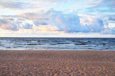 Gün batımında fırtınadan sonra Baltık Denizi 'nin üzerinde yığınla kümülüs bulutu olan mavi gökyüzü. İnsan izleri ve kum dokusu, yakın plan. Idyllic manzara. Ilık güneş ışığı. Seyahat yerleri, eko turizm