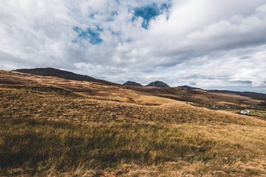 Karanlık fırtına gökyüzünün altındaki Paps of Jura 'nın (Beinn an ir) en yüksek dağı yakınındaki vadinin panoramik manzarası. Dramatik bulutlar. Jura Adası, Inner Hebrides, İskoçya, İngiltere. Atmosferik manzara.