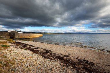 Eski deniz fenerine boş bir gezinti alanı, çakıllı plaj yakınlaşması. Dramatik bulut manzarası. Ardrishaig, Crinan Kanalı, İskoçya, İngiltere. Seyahat yerleri, gezi teması