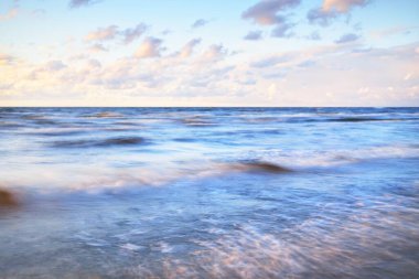 Gök gürültülü bir fırtınadan sonra denizin üstünde destansı pembe gün batımı bulutları. Dramatik bir gökyüzü. Dalgalar ve su dokuya sıçrar. Idyllic deniz manzarası. Kavramsal görüntü, uzun pozlama. Resim gibi bir manzara.