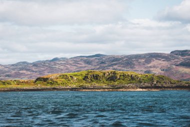 Yat manzaralı Jura adasının batı kıyısındaki kayalık kıyılara (uçurumlara) yelken açmak. Parlak bulutlu dramatik günbatımı gökyüzü. Inner Hebrides, İskoçya, İngiltere. Seyahat yerleri, işaretler