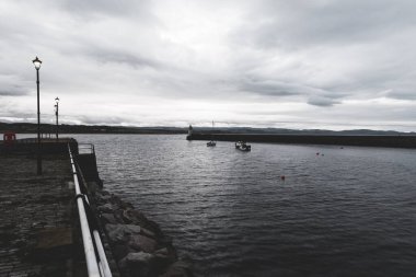 Eski deniz fenerine doğru boş bir gezinti, yakın plan. Arka planda kayalık kıyılar var. Dramatik bulut manzarası. Ardrishaig, Crinan Kanalı, İskoçya, İngiltere. Seyahat yerleri, gezi teması