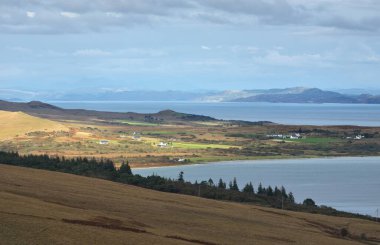 Jura adasının kıyılarının panoramik manzarası, dağları ve vadileri sudan. Bulutlu mavi gökyüzü. Fırtınalı hava. Paps of Jura, Inner Hebrides, İskoçya, İngiltere