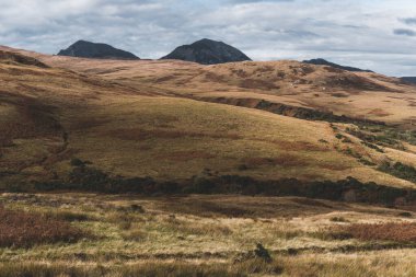 Karanlık fırtına gökyüzünün altındaki Paps of Jura 'nın (Beinn an ir) en yüksek dağı yakınındaki vadinin panoramik manzarası. Dramatik bulutlar. Jura Adası, Inner Hebrides, İskoçya, İngiltere. Atmosferik manzara.