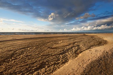 Destansı kümülüs bulutları, fırtınadan sonra kumlu Baltık deniz kıyısında. Kuru nehir, yakın çekim kum dokusu. - Letonya. Dramatik bir gökyüzü. Ekoloji, çevre koruma, kararsız hava, iklim değişikliği