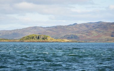 Jura adasının kıyılarının panoramik manzarası, dağları ve vadileri sudan. Bulutlu mavi gökyüzü. Paps of Jura, Inner Hebrides, İskoçya, İngiltere