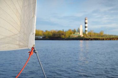 Deniz feneri, menzil işareti ve günbatımında dalgalar. Baltık Denizi, Letonya. Idyllic manzara. Yat manzaralı, beyaz yelkenli yakın çekim. Ulaşım, yelken, yön bulma. Umut ve barışın sembolü