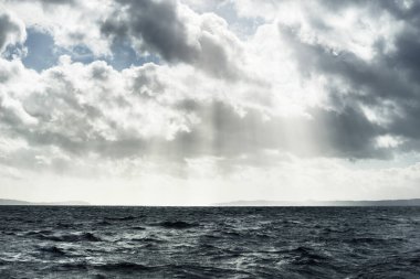Sudan kayalık nehir kıyılarının panoramik görüntüsü. Arka planda ağaçlar, tepeler ve dağlar var. Bulutlu mavi gökyüzü. Gare Loch, Clyde Firth, İskoçya, İngiltere