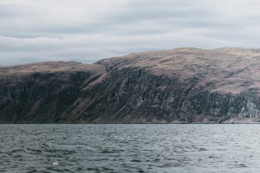 Yat manzaralı Jura adasının batı kıyısındaki kayalık kıyılara (uçurumlara) yelken açmak. Fırtınadan sonra dramatik bulutlar. Inner Hebrides, İskoçya, İngiltere. Atmosferik manzara