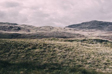 Karanlık fırtına gökyüzünün altındaki Paps of Jura 'nın (Beinn an ir) en yüksek dağı yakınındaki vadinin panoramik manzarası. Dramatik bulutlar. Jura Adası, Inner Hebrides, İskoçya, İngiltere. Atmosferik manzara.