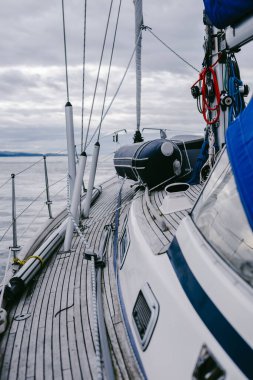 Bulutlu bir günde, Jura adasının kayalık kıyılarında seyir halindeki ahşap meşe güvertesiyle donatılmış modern bir yat. Inner Hebrides, İskoçya, İngiltere. Spor, eğlence, gezi, seyahat yerleri.