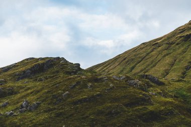 Yeşil kayalık kıyılar ve dramatik mavi gökyüzünün altındaki tepeler. Lomond Gölü ve Trossachs Ulusal Parkı, Inner Hebrides, İskoçya, İngiltere. Seyahat yerleri, eko turizm, yürüyüş, boş zaman aktiviteleri
