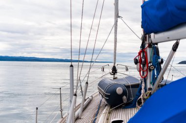 Bulutlu bir günde, Jura adasının kayalık kıyılarında seyir halindeki ahşap meşe güvertesiyle donatılmış modern bir yat. Inner Hebrides, İskoçya, İngiltere. Spor, eğlence, gezi, seyahat yerleri.