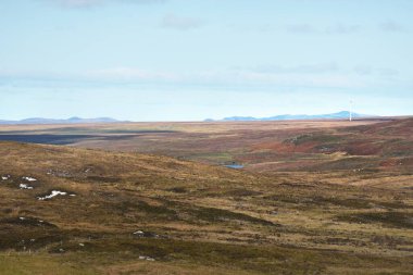 Islay adasının kayalık kıyılarının, vadilerinin ve tepelerinin havadan görünüşü. Arka planda rüzgar türbini var. Inner Hebrides, Argyll ve Bute, İskoçya, İngiltere